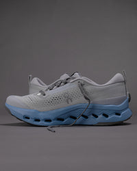 Gray and blue athletic shoe on a gray background
Men's On Cloudsurfer Trail 2 in Rock/Niagara – Plush Cushioning Trail Running Shoe