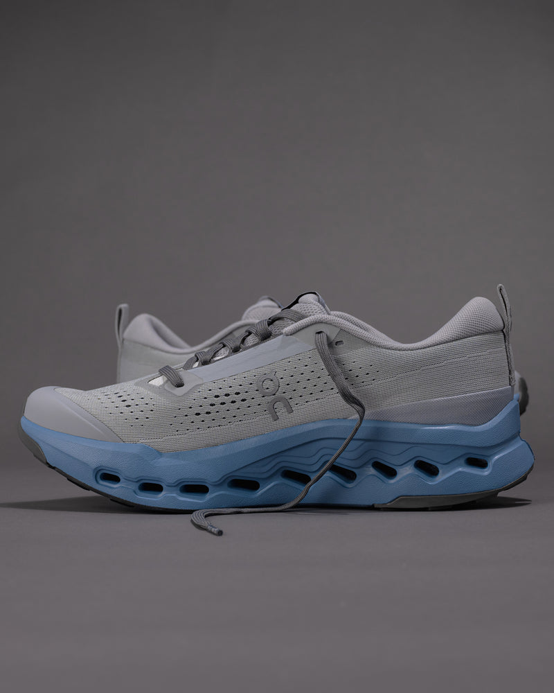 Gray and blue athletic shoe on a gray background
Men's On Cloudsurfer Trail 2 in Rock/Niagara – Plush Cushioning Trail Running Shoe