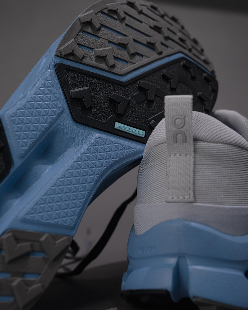 Close-up of a shoe with blue sole and gray side, On Running logo visible.
Men's On Cloudsurfer Trail 2 in Rock/Niagara – Plush Cushioning Trail Running Shoe