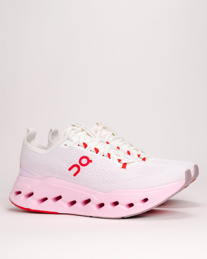 Side view of white and pink Women’s On Cloudsurfer Max shoes in Ivory / Peony color with "On" brand logo on a white background