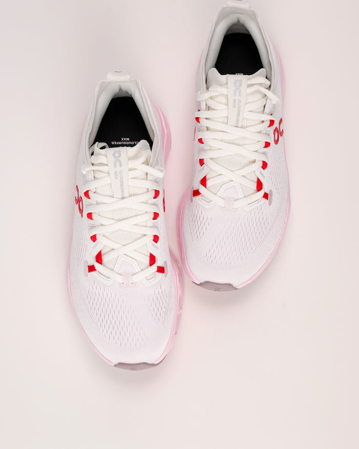 Women’s On Cloudsurfer Max cushioned running shoes in Ivory / Peony shoes with red accents on a light  background