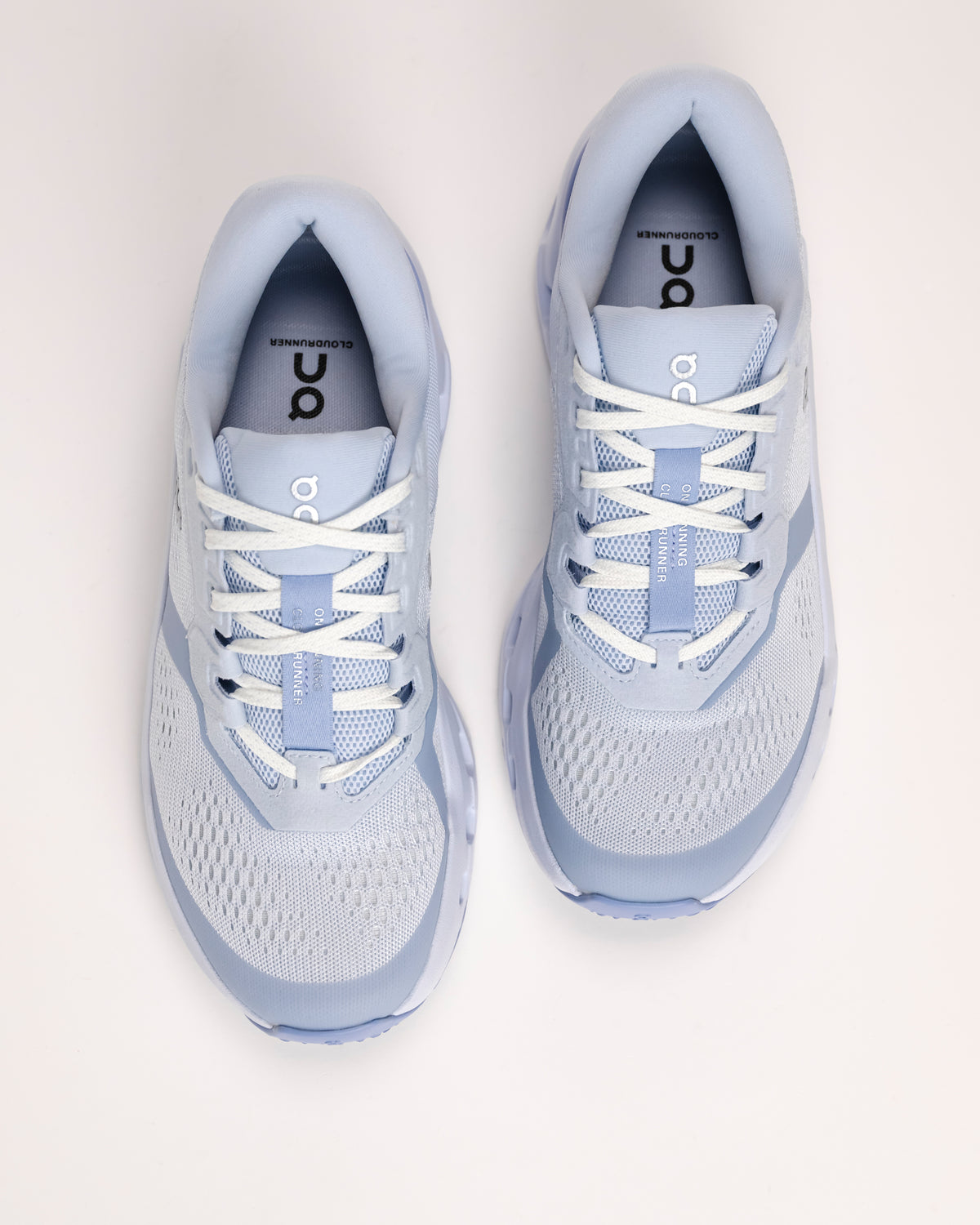 Pair of light blue On Cloudrunner 3 cushioned road running shoes on a white background