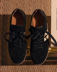 Pair of black Gabor sneakers on a glass surface.