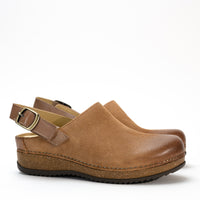 Side profile of the Dansko Merrin mule in high-quality leather, featuring a sleek sling-back strap and cork midsole.