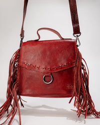 Front view of Hidden bag in Cherry leather with magnetic flap closed, showcasing fringe and O‑ring hardware