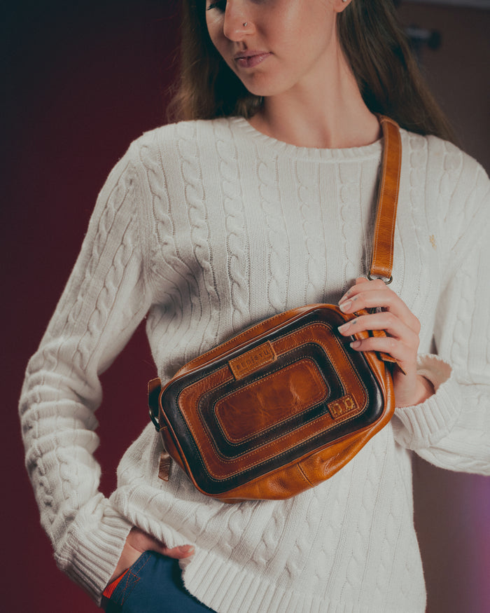 Woman wearing the Bed|Stü Shy compact leather crossbody bag in Pecan leather with light color knit sweater
