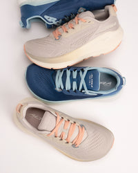 Overhead shot of stacked Altra FWD VIA 2 shoes in tan and navy on a white background