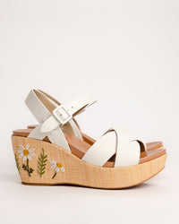 The Ava 2.0 in White / Cream with Floral Embroidery is a modernized tribute to the legendary 1970s "Buffalo Sandal" that put Kork-Ease on the fashion map. This specific edition pairs smooth, cream-colored leather straps with a beautifully textured raffia-wrapped wedge, featuring delicate, multi-colored floral embroidery for a soft, bohemian touch. It’s a design that feels both nostalgic and fresh, offering a substantial platform look that doesn't feel heavy or clunky.