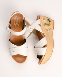 The Ava 2.0 in White / Cream with Floral Embroidery is a modernized tribute to the legendary 1970s "Buffalo Sandal" that put Kork-Ease on the fashion map. This specific edition pairs smooth, cream-colored leather straps with a beautifully textured raffia-wrapped wedge, featuring delicate, multi-colored floral embroidery for a soft, bohemian touch. It’s a design that feels both nostalgic and fresh, offering a substantial platform look that doesn't feel heavy or clunky.