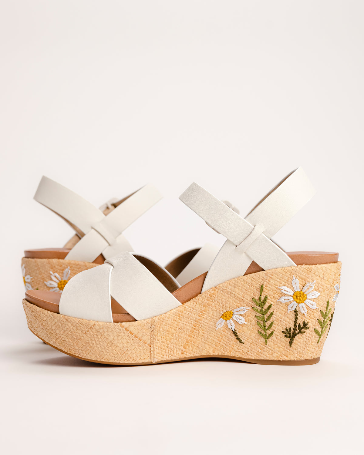 The Ava 2.0 in White / Cream with Floral Embroidery is a modernized tribute to the legendary 1970s "Buffalo Sandal" that put Kork-Ease on the fashion map. This specific edition pairs smooth, cream-colored leather straps with a beautifully textured raffia-wrapped wedge, featuring delicate, multi-colored floral embroidery for a soft, bohemian touch. It’s a design that feels both nostalgic and fresh, offering a substantial platform look that doesn't feel heavy or clunky.