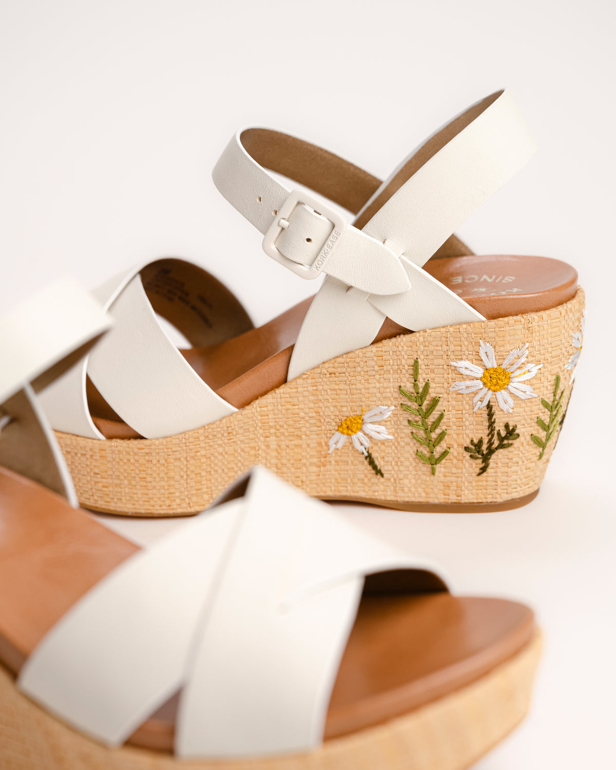 The Ava 2.0 in White / Cream with Floral Embroidery is a modernized tribute to the legendary 1970s "Buffalo Sandal" that put Kork-Ease on the fashion map. This specific edition pairs smooth, cream-colored leather straps with a beautifully textured raffia-wrapped wedge, featuring delicate, multi-colored floral embroidery for a soft, bohemian touch. It’s a design that feels both nostalgic and fresh, offering a substantial platform look that doesn't feel heavy or clunky.