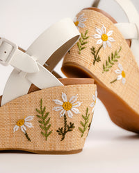 The Ava 2.0 in White / Cream with Floral Embroidery is a modernized tribute to the legendary 1970s "Buffalo Sandal" that put Kork-Ease on the fashion map. This specific edition pairs smooth, cream-colored leather straps with a beautifully textured raffia-wrapped wedge, featuring delicate, multi-colored floral embroidery for a soft, bohemian touch. It’s a design that feels both nostalgic and fresh, offering a substantial platform look that doesn't feel heavy or clunky.