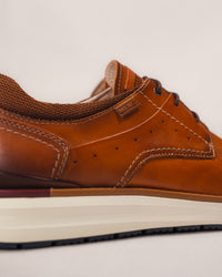 Close-up of the leather logo tag and stitching of the Pikolinos MANACOR men’s sneaker in brown leather