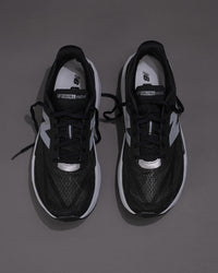 Black and white sneakers on a gray backgroundMen’s New Balance FuelCell Rebel v5 in Black/White – Lightweight Neutral Trainer