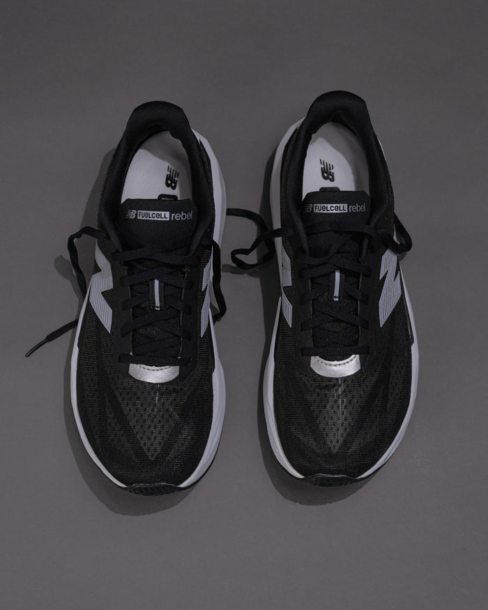 Black and white sneakers on a gray backgroundMen’s New Balance FuelCell Rebel v5 in Black/White – Lightweight Neutral Trainer