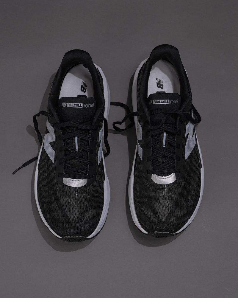 Black and white sneakers on a gray backgroundMen’s New Balance FuelCell Rebel v5 in Black/White – Lightweight Neutral Trainer