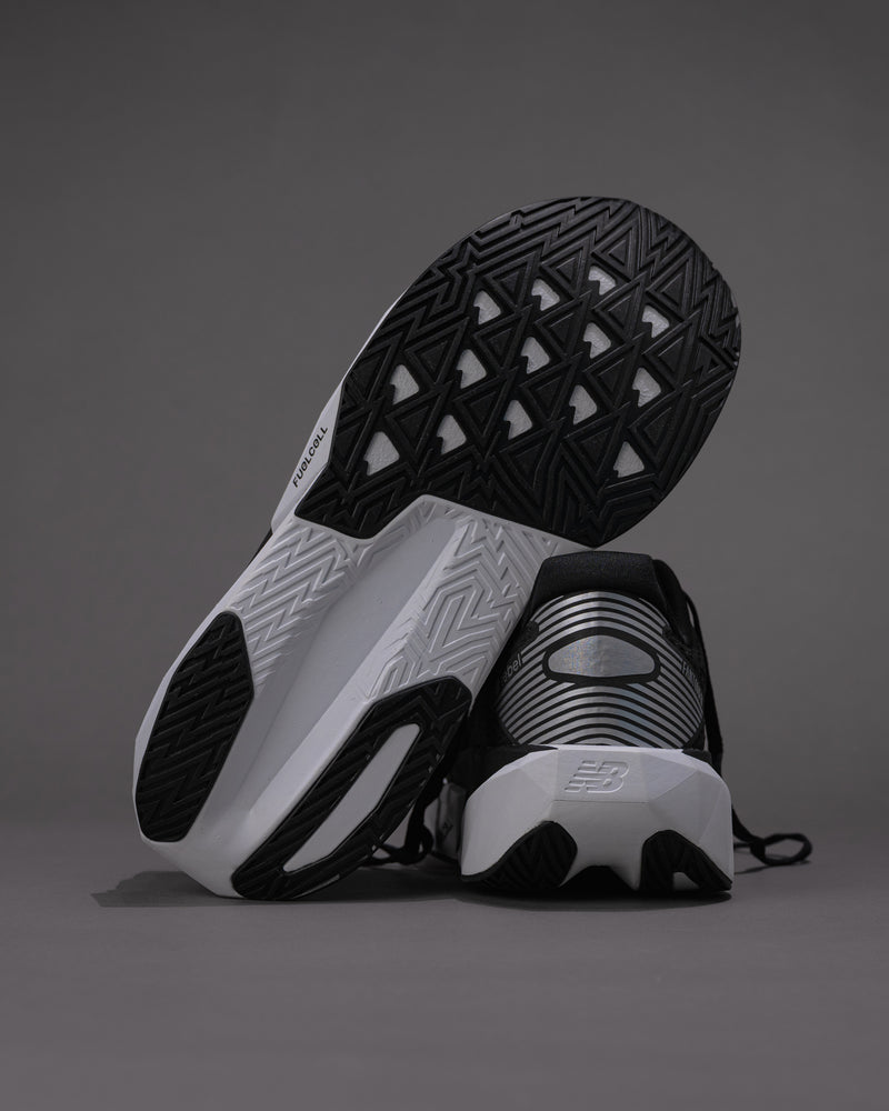 Black and white athletic shoes on a gray background Men’s New Balance FuelCell Rebel v5 in Black/White – Lightweight Neutral Trainer