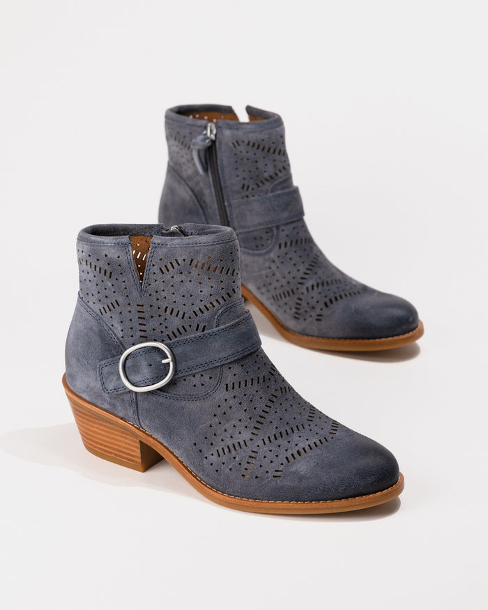 Pair of blue suede ankle boots with brown soles on a white background