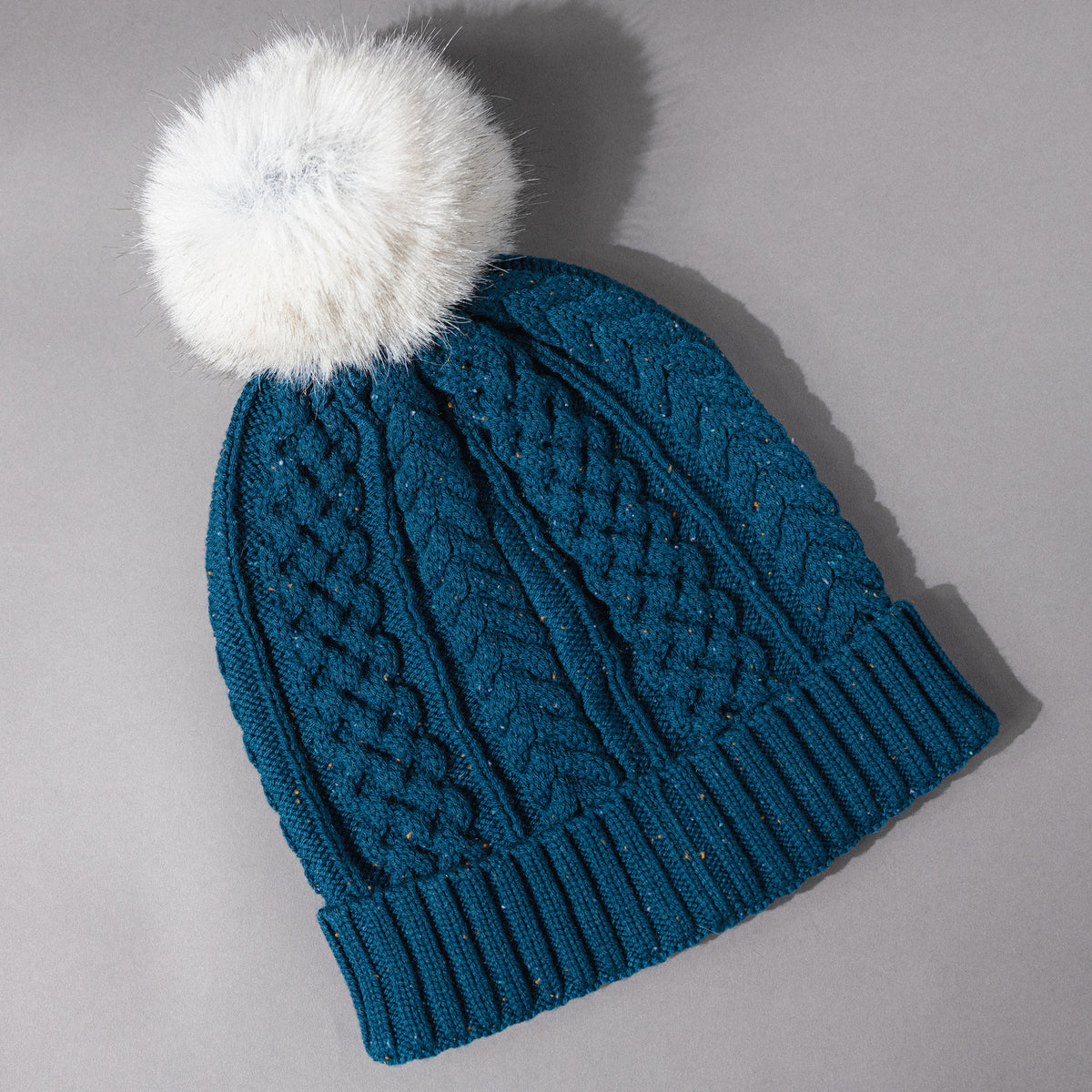 Backside overhead view of the Women's Smartwool Lodge Girl Soft Merino Knit Beanie with Faux Fur Pom in Twilight