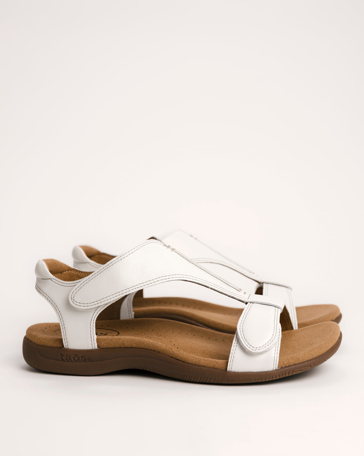 Women's Taos sandals. The Show comfort sandal features a premium white leather upper, adjustable straps, and a contoured cushioned footbed with arch support for all-day wear.