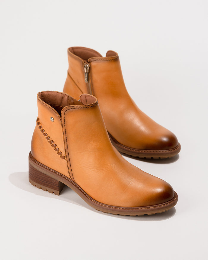 Angled side-overhead view of the Pikolinos Medina heeled ankle boot in Almond leather, showing zip fastening and block heel.