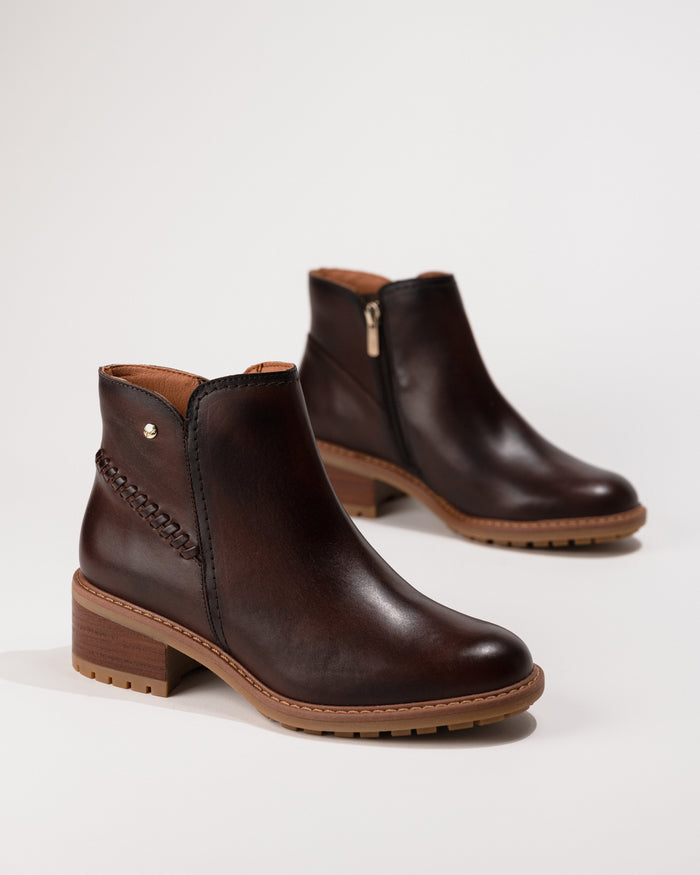 Angled side-overhead view of the Pikolinos Medina heeled ankle boot in caoba leather, showing zip fastening and block heel.