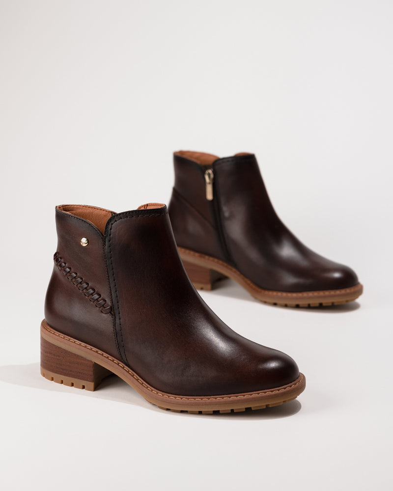 Angled side-overhead view of the Pikolinos Medina heeled ankle boot in caoba leather, showing zip fastening and block heel.