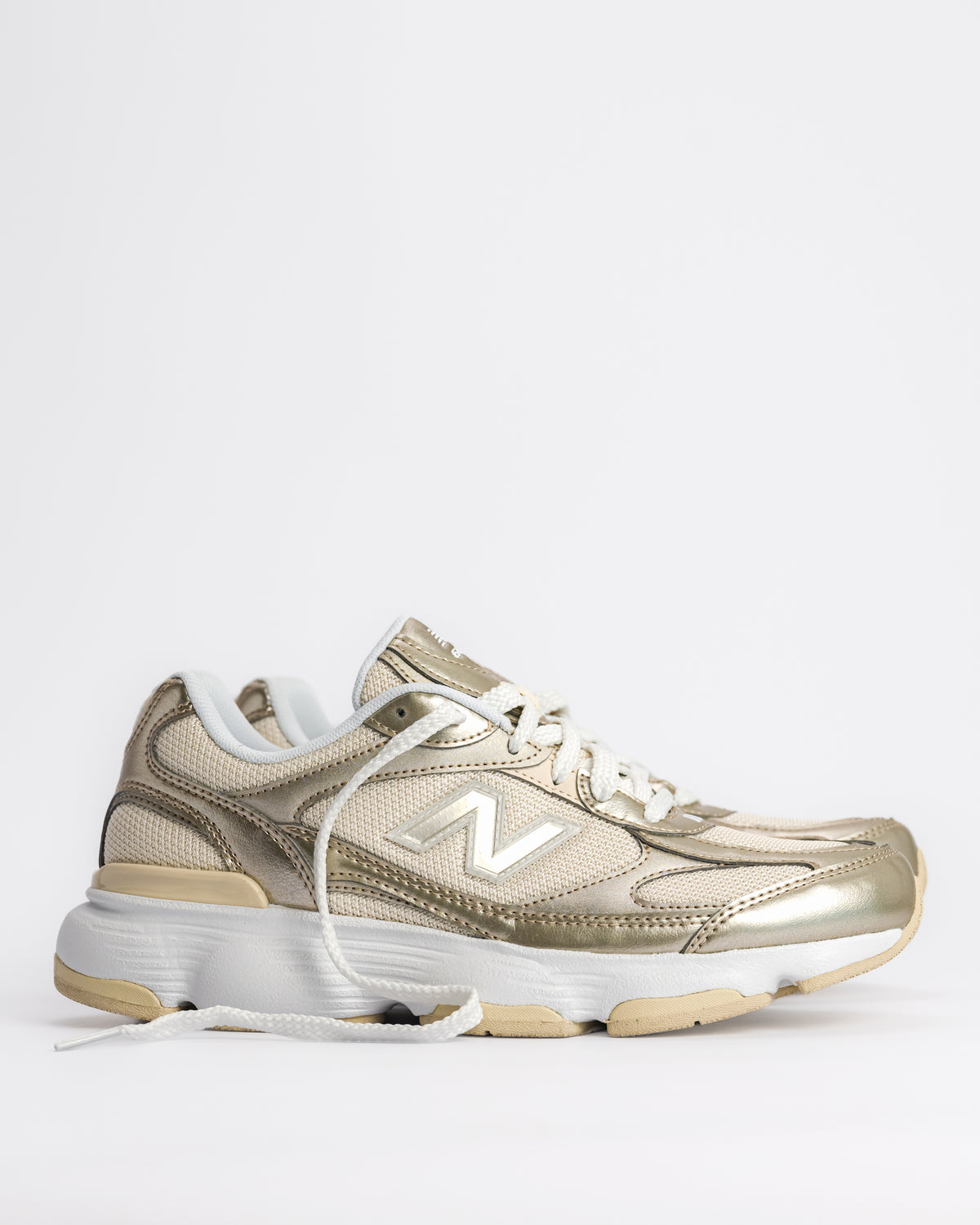 A New Balance 603 sneaker in metallic gold and beige with white laces and a chunky white and beige sole, shown from a side profile on a light gray background. W60347S 