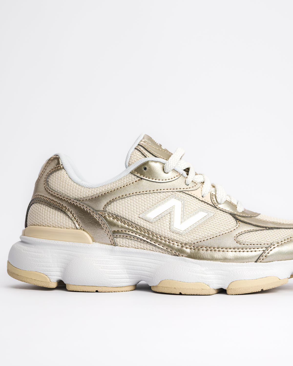 A New Balance 603 sneaker in metallic gold and beige with white laces and a chunky white and beige sole, shown from a side profile on a light gray background. W60347S 