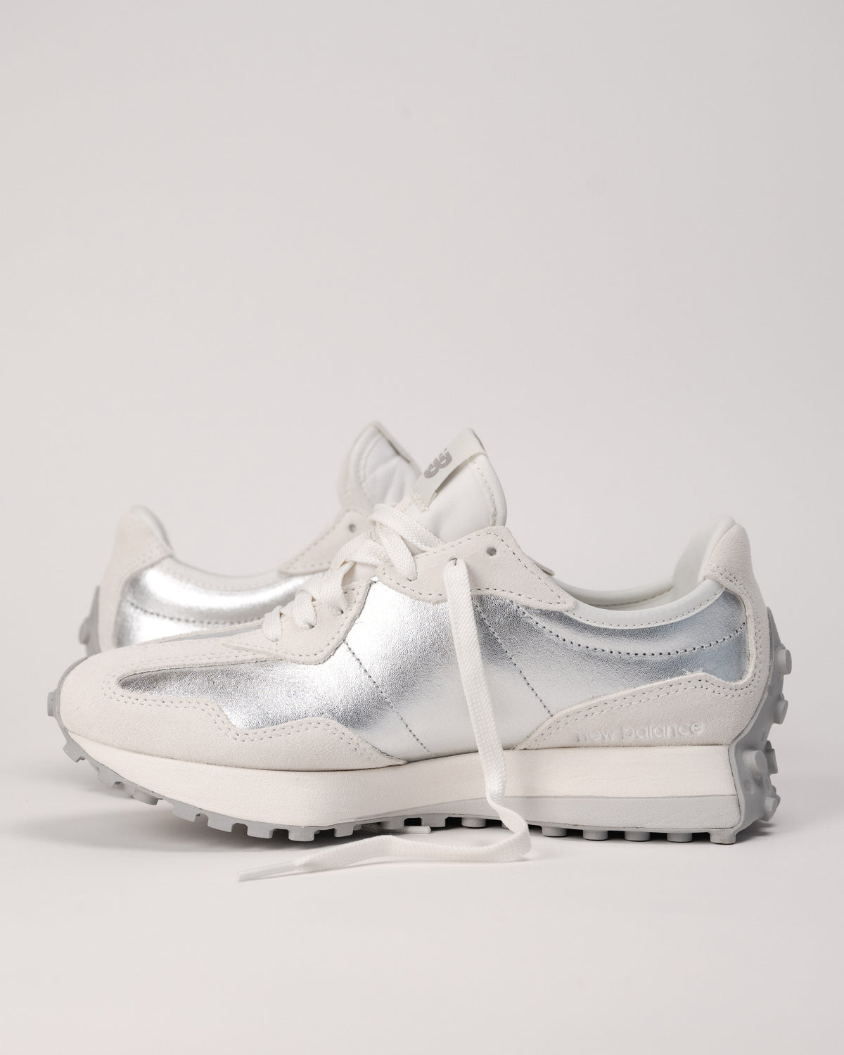 Street-style flat lay of New Balance 327 retro sneakers in Silver metallic finish
